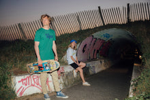 Charger l'image dans la galerie, homme avec un skate portant t shirt vintage tiga logo bleu fond vert