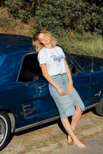 Load image into Gallery viewer, femme portant t shirt tiga logo bleu fond blanc vintage sur une belle voiture
