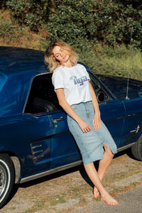 femme portant t shirt tiga logo bleu fond blanc vintage sur une belle voiture